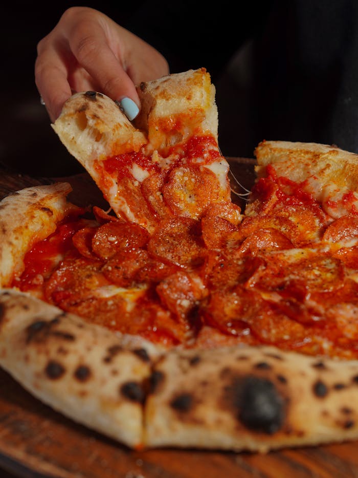 pexels-photo-20844861 Delicious pepperoni pizza slice being lifted from a wood-fired pie with melted cheese.