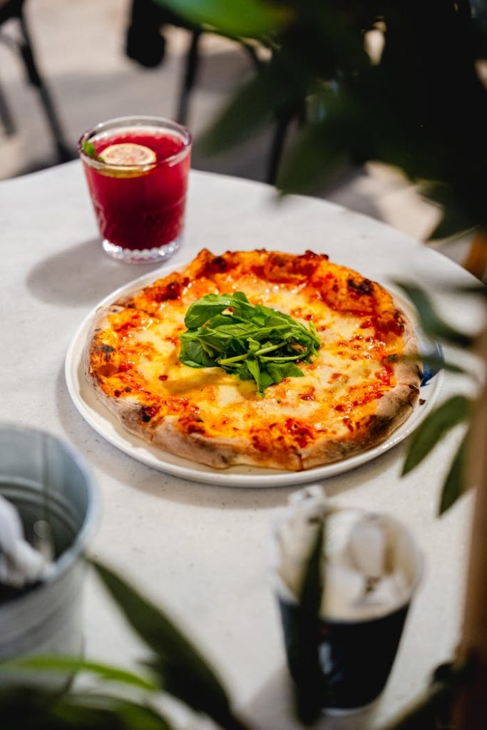 pexels-photo-31587857 Close-up of a freshly baked Margherita pizza topped with arugula on an outdoor table.